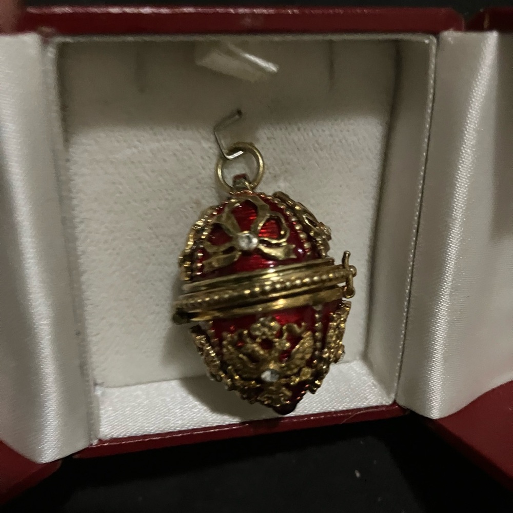 Red and gold guilloche enamel egg pendent that opens up .